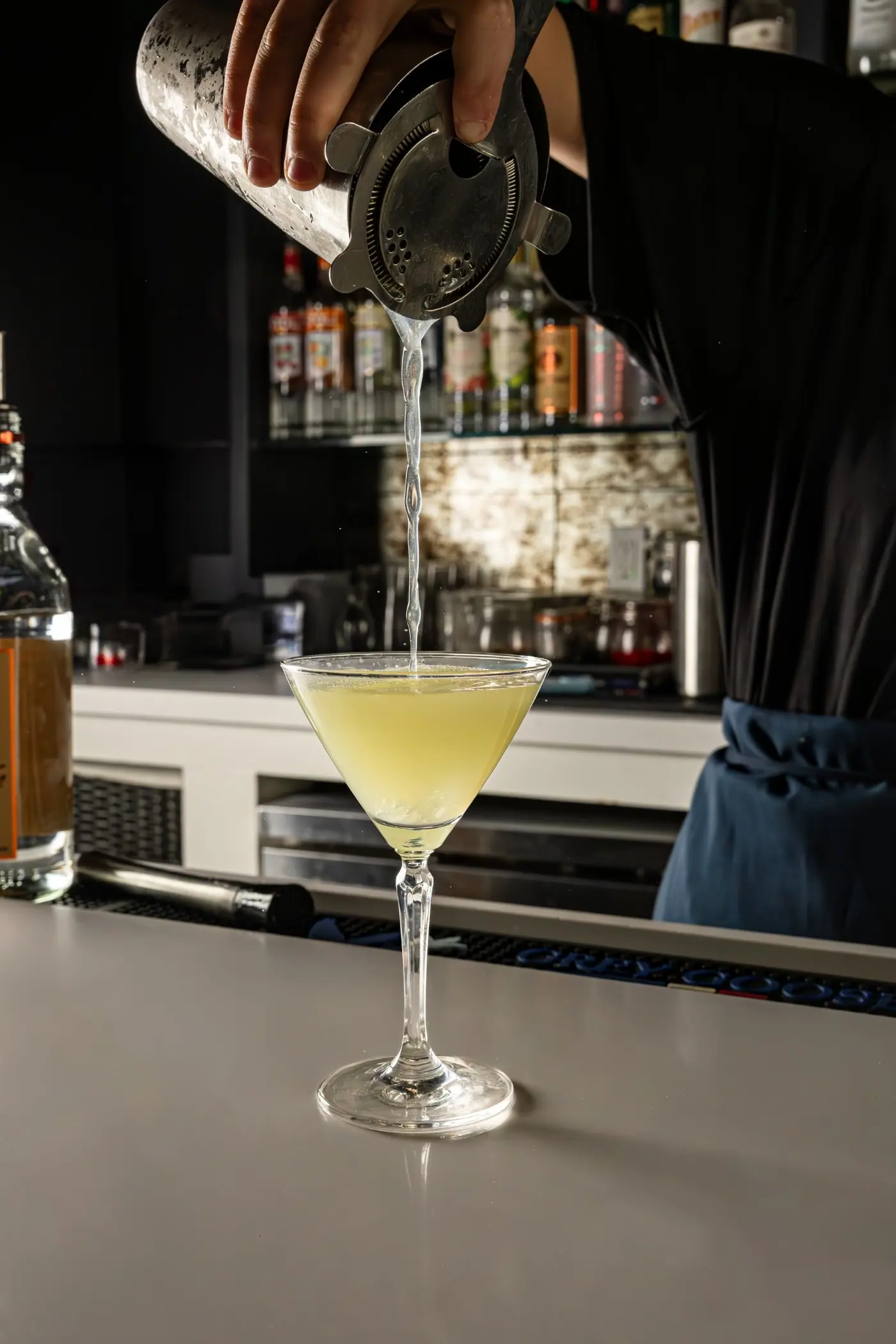 A martini being poured at the bar late in the evening